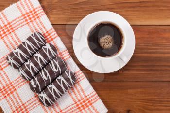 Coffee and cookies glazed on the tablecloth on a kitchen table.