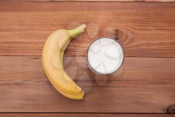 Glass of milk and bananas on a wooden background. View from above .
