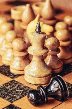Chess leader led king his army white wooden figures and defeated enemy black pawn. Concept game