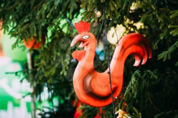 Christmas Decoration, Vintage Wooden Christmas Toy In Form Of A Red Cock Hanging On Christmas Tree In Riga, Latvia. Close-up. Winter Holiday Celebration. New Year In Europe.