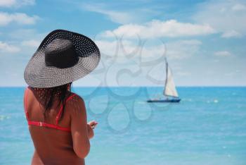 woman on the beach looking at the fleeing sailboat