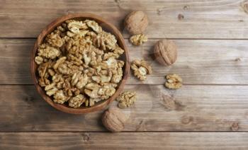 Walnuts in wooden bowl on wooden table