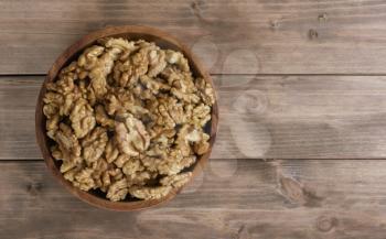 Walnuts in wooden bowl on wooden table