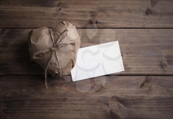 Heart wrapped in brown kraft paper with a note, on wooden background