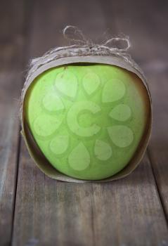 green apple wrapped in paper and tie a string on the wooden table
