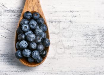 Spoon full of fresh black currant in a wooden table background