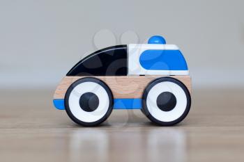 Simple wood and plastic toy police car isolated on a wooden floor