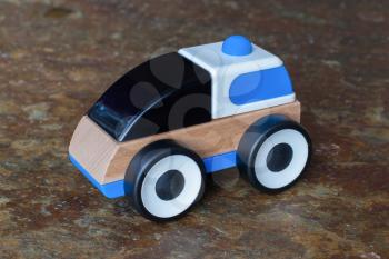 Simple wood and plastic toy police car isolated on a granite floor