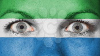 Close up of eyes. Painted face with flag of Sierra Leone