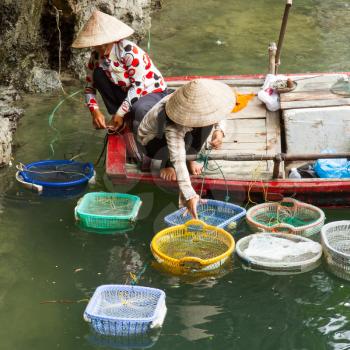 HA LONG BAY, VIETNAM AUG 10, 2012 - Food seller in boat. Many Vietnamese people try to sell different goods to tourists. Ha Long Bay, Vietnam