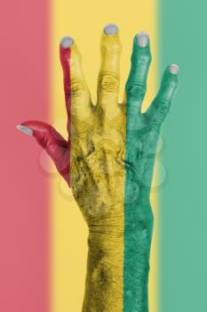 Hand of an old woman wrapped in flag of Guinea