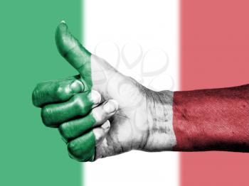 Old woman with arthritis giving the thumbs up sign, wrapped in flag pattern, Italy