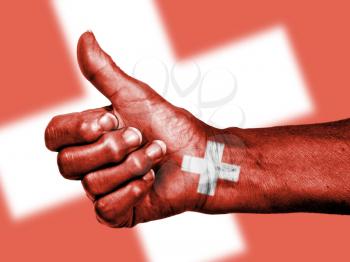 Old woman with arthritis giving the thumbs up sign, wrapped in flag pattern, Switzerland