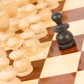 Black pawn on a wooden chessboard, old handcarved set