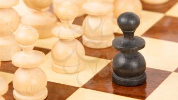 Black pawn on a wooden chessboard, old handcarved set