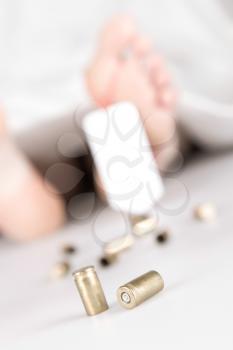 Dead body with toe tag, bullets and a white sheet