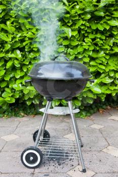 Old black barbecue being used, smoke coming from the top