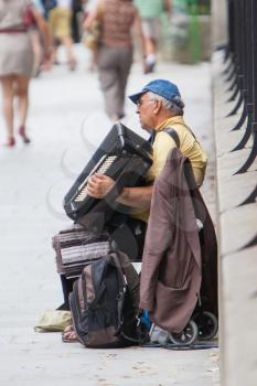 PARIS, FRANCE - JULY 27, 2013: An accordion player sitting on a bridge in Paris and plays French songs. Paris is the most visited city in the world with 15.6 million international arrivals in 2011.