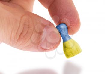 Hand holding wooden pawn with a flag painting, selective focus, Ukraine