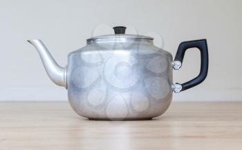 Old metal tea pot isolated on wooden table