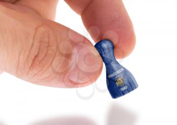 Hand holding wooden pawn with a flag painting, selective focus, Wisconsis