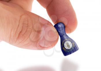 Hand holding wooden pawn with a flag painting, selective focus, Kentucky