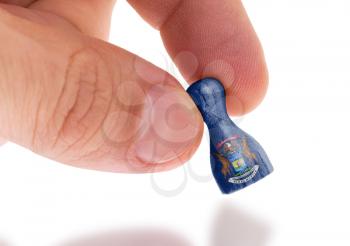 Hand holding wooden pawn with a flag painting, selective focus, Michigan