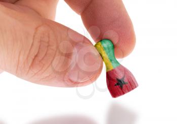 Hand holding wooden pawn with a flag painting, selective focus, Guinea-Bissau