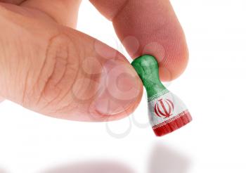 Hand holding wooden pawn with a flag painting, selective focus, Iran