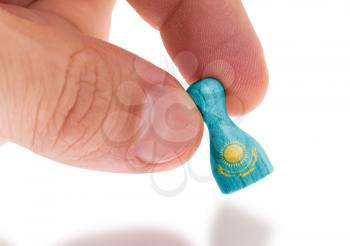 Hand holding wooden pawn with a flag painting, selective focus, Kazakhstan