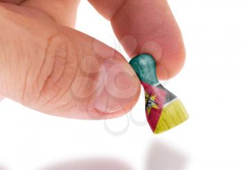 Hand holding wooden pawn with a flag painting, selective focus, Mozambique