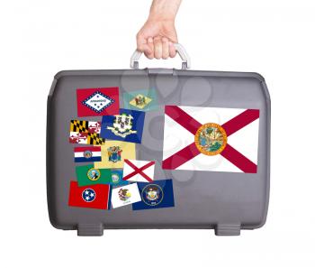 Used plastic suitcase with stains and scratches, stickers of US States, Florida