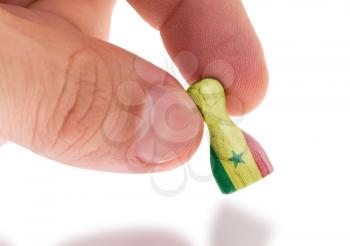 Hand holding wooden pawn with a flag painting, selective focus, Senegal