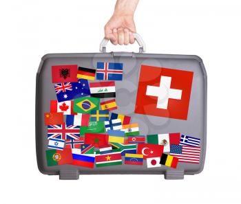 Used plastic suitcase with lots of small stickers, large sticker of Switzerland