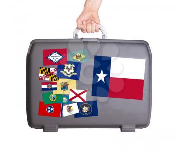 Used plastic suitcase with stains and scratches, stickers of US States, Texas