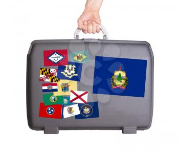 Used plastic suitcase with stains and scratches, stickers of US States, Vermont