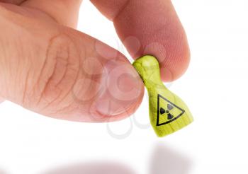 Hand holding wooden pawn with a painting, selective focus, radiation