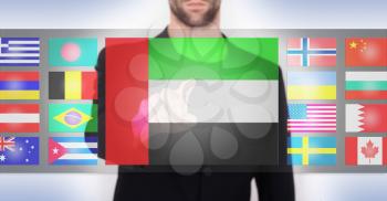 Hand pushing on a touch screen interface, choosing language or country, UAE