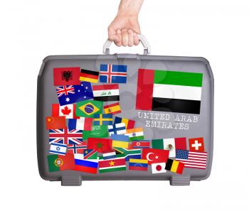 Used plastic suitcase with lots of small stickers, large sticker of the UAE