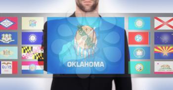 Hand pushing on a touch screen interface, choosing a state, Oklahoma
