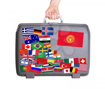 Used plastic suitcase with lots of small stickers, large sticker of Kyrgyzstan