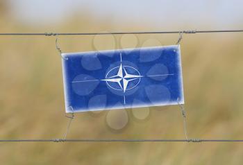 Border fence - Old plastic sign with a flag - NATO