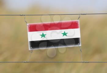 Border fence - Old plastic sign with a flag - Syria