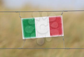 Border fence - Old plastic sign with a flag - Italy