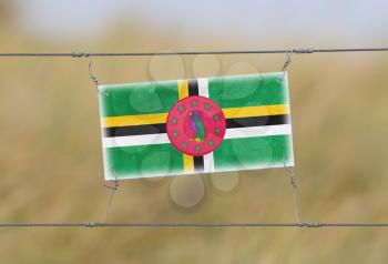 Border fence - Old plastic sign with a flag - Dominica