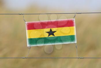Border fence - Old plastic sign with a flag - Ghana