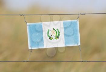 Border fence - Old plastic sign with a flag - Guatemala