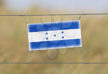 Border fence - Old plastic sign with a flag - Honduras