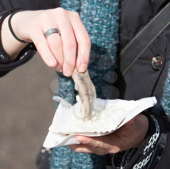 Dutch woman is eating typical raw herring with onions
