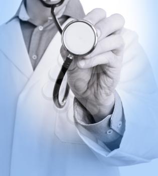 Close up of a Doctor's hand, holding a stethoscope outstretched towards the viewer, medical blue